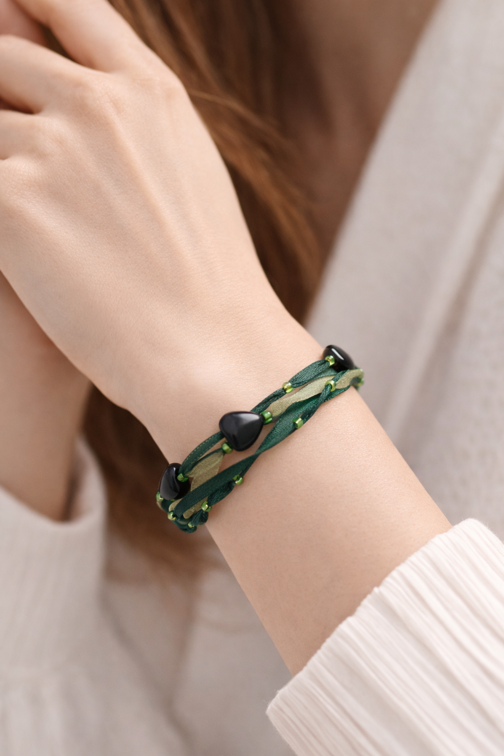 Bracelet Syléra : Trois rubans aux nuances de vert entrelacés, ponctués de perles et de cœurs profonds, pour une élégance naturelle et lumineuse au poignet.